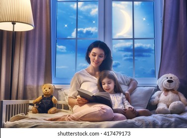 Family reading bedtime. Pretty young mother reading a book to her daughter.