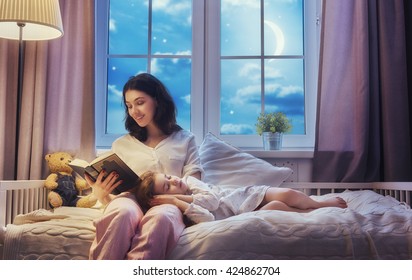 Family Reading Bedtime. Pretty Young Mother Reading A Book To Her Daughter.