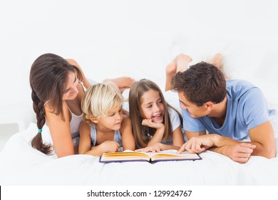 Family Reading Book On The Bed In The Bedroom