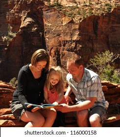 A Family Reading A Book Together In Zion National Park Utah.