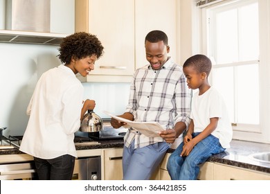 Family Reading The Newspaper In The Kitchen