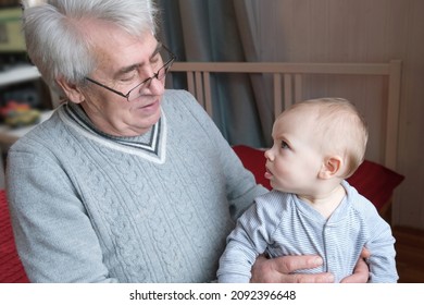 Family Relations Of Elderly 60s Male And Baby Girl. Happy Old Man Holds A Little Child On Hands. Gentle Hug And Love For Caucasian Grandchild In Slow Motion. Enjoy Family Time.