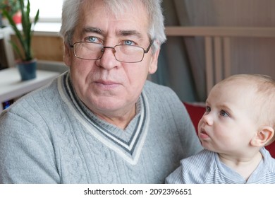 Family Relations Of Elderly 60s Male And Baby Girl. Happy Old Man Holds A Little Child On Hands. Gentle Hug And Love For Caucasian Grandchild In Slow Motion. Enjoy Family Time.