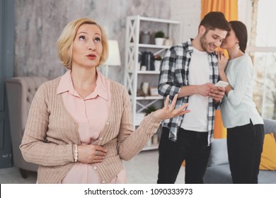 Family Relations. Sad Elderly Woman Standing Near The Married Couple While Being Not Happy About Them