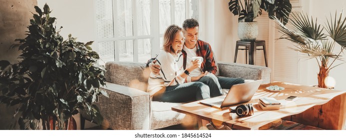 Family Relationship. Happy Couple At Home On The Couch Watching Movie Using Laptop. Wide Screen, Panoramic