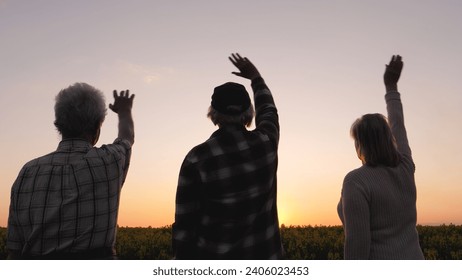 Family relatives people wave goodbye to sun at sunset. They are standing outdoors enjoying warm summer evening. Silluet people look to future with hope. Ritual of seeing off day.