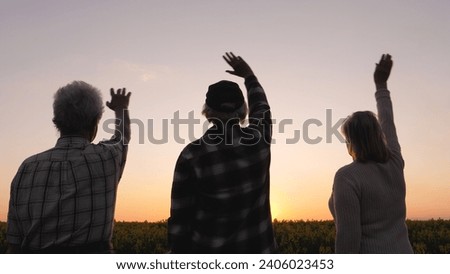 Family relatives people wave goodbye to sun at sunset. They are standing outdoors enjoying warm summer evening. Silluet people look to future with hope. Ritual of seeing off day.