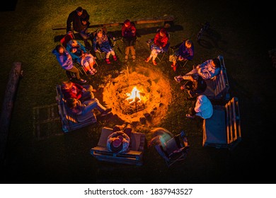  family relaxing and enjoying summer evening around campfire, singing and telling stories,  the joy of being together, long exposure drone pkotography, soft focus