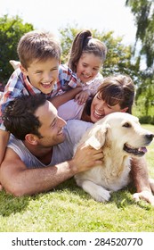 Family Relaxing In Garden With Pet Dog