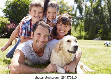 Family Relaxing In Garden With Pet Dog