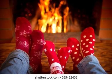 Family Relaxing At Home. Feet In Christmas Socks Near Fireplace. Winter Holiday Concept