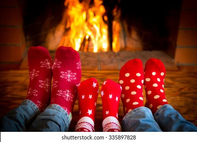 Family Relaxing At Home. Feet In Christmas Socks Near Fireplace. Winter Holiday Concept