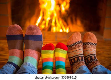 Family Relaxing At Home. Feet In Christmas Socks Near Fireplace. Winter Holiday Concept