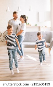 Family Relaxing At Home. Young Caucasian Family With A Tiny Son-in-law Looks Into The Kitchen. Children Live In Love And Happiness.