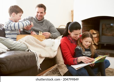 Family Relaxing Indoors Playing Chess And Reading Book