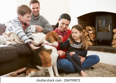Family Relaxing Indoors And Stroking Pet Dog