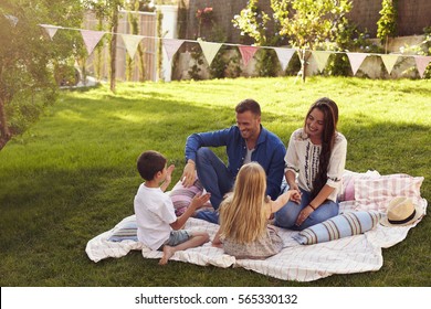 Family Relaxing On Blanket In Garden