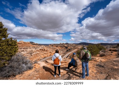 Family relaxing on hiking trail. Friends standing on top of the mountain. Potash Road or the Lower Colorado Scenic Byway, Moab, Utah,USA