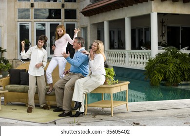 Family Relaxing On Patio Together Playing Air Guitar