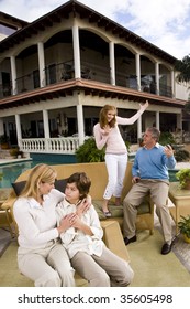Family Relaxing On Patio Together Playing Air Guitar