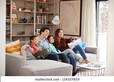 Family Relaxing On Sofa At Home Watching Television