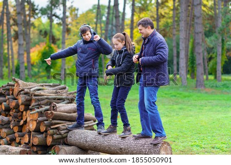 family relaxing outdoor in autumn city park, happy people together, parents and children, they standing on a log, playing, talking and smiling, beautiful nature