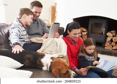 Family Relaxing Reading Book And Using Digital Tablet