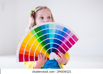 Family Remodeling House. Home Remodel And Renovation. Kids Painting Walls With Colorful Brush And Roller. Children Paint Wall. Choice Of Bright Color On Sample Palette For Child Nursery Or Kid Room.