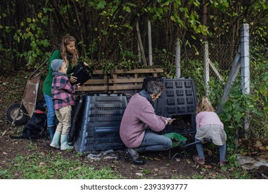 Family removing compost from a composter in garden, and composting kitchen waste in composter. Concept of composting and sustainable organic gardening. - Powered by Shutterstock