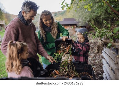 Family removing compost from a composter in garden, and composting kitchen waste in composter. Concept of composting and sustainable organic gardening. - Powered by Shutterstock