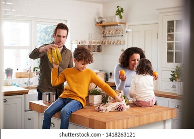 Family Returning Home From Shopping Trip Using Plastic Free Bags Unpacking Groceries In Kitchen