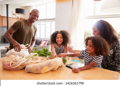 Family Returning Home From Shopping Trip Unpacking Plastic Free Grocery Bags