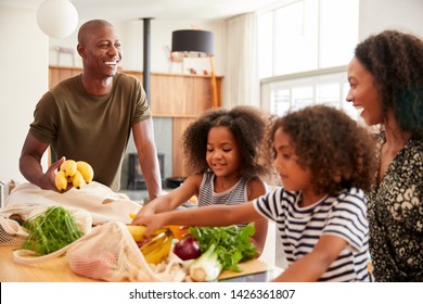 Family Returning Home From Shopping Trip Unpacking Plastic Free Grocery Bags