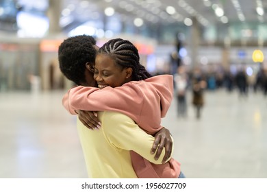 Family Reunion In Airport. Happy Black Male Hugging Excited Woman After Plane Arrival In Terminal. Loving Coule Met After Covid-19 Epidemic Lockdown. Romantic Male And Female Embrace After Trip Abroad