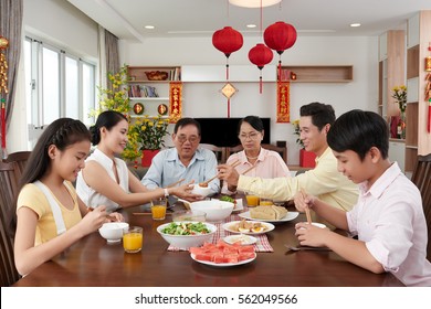Family reunion dinner for Tet celebration at home; couplets with best wishes for coming year in the background