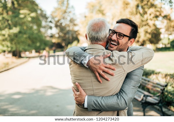 Family reunion.\
Father and son hugging\
outdoors.