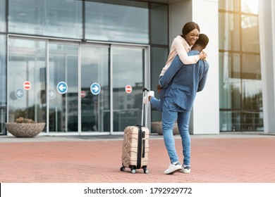 Family Reunion. Happy Black Couple Meeting At Airport After Arrival, Loving Man Lifting Wife In Air, Copy Space