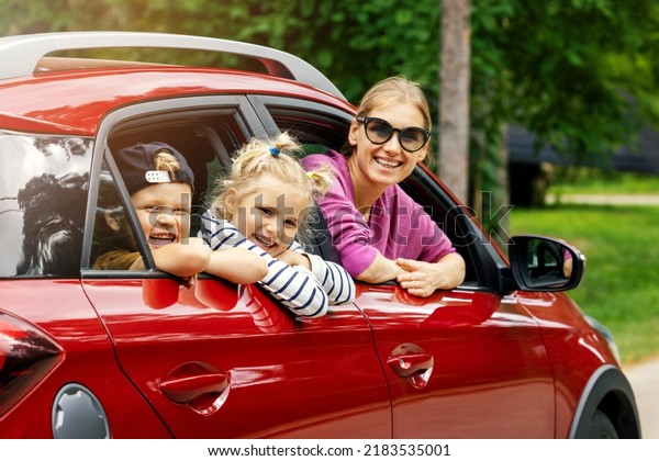 family road trip. mother with children smiling and\
leaning out of the car\
window