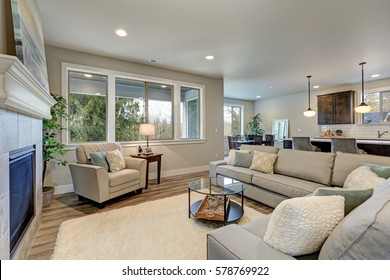 Family room interior features grey linen sectional lined with colorful pillows facing fireplace with grey tile surround across from glass top coffee table atop white soft rug. Northwest, USA - Powered by Shutterstock