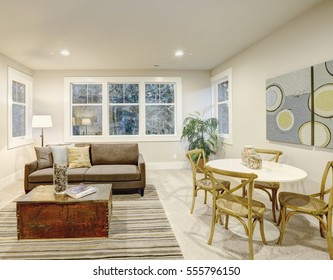 Family room interior with gray sofa facing a trunk coffee table atop a gray and brown striped rug next to white game table with wicker chairs. 
 Northwest, USA