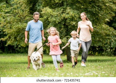 Family Running With Dog And Having Fun In Summer