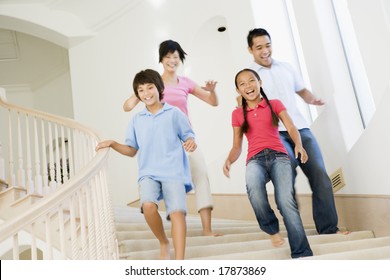 Family Running Down Staircase Smiling