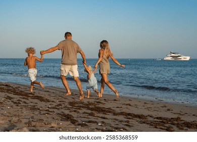 Family Running and Holding Hands on the Beach by the Ocean at Su