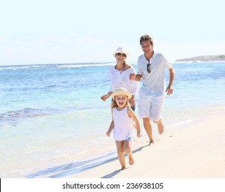 Family running on a white sandy beach