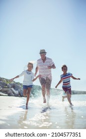 Family Running In Water On Beach