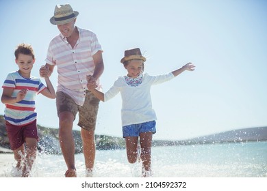 Family Running In Water On Beach