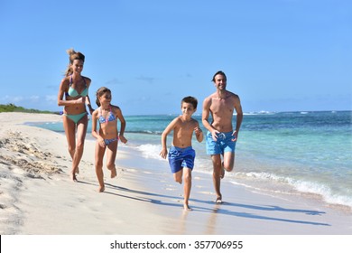 Family Runnning On A Sandy Beach In Caribbean Island