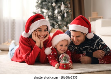 Family in Santa hats playing with snow globe at home - Powered by Shutterstock