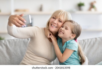 Family Selfie. Portrait of multi-generation family taking selfie photo together at home indoors. Happy grandmother posing with her little grandchild using mobile phone. Bonding And Lifestyle Concept - Powered by Shutterstock