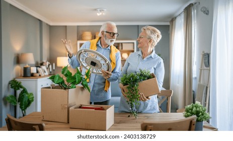 family senior couple man woman husband and wife pensioner grandfather grandmother moving in new apartment taking their stuff belongings and plants in or out of boxes packing or unpacking real people - Powered by Shutterstock